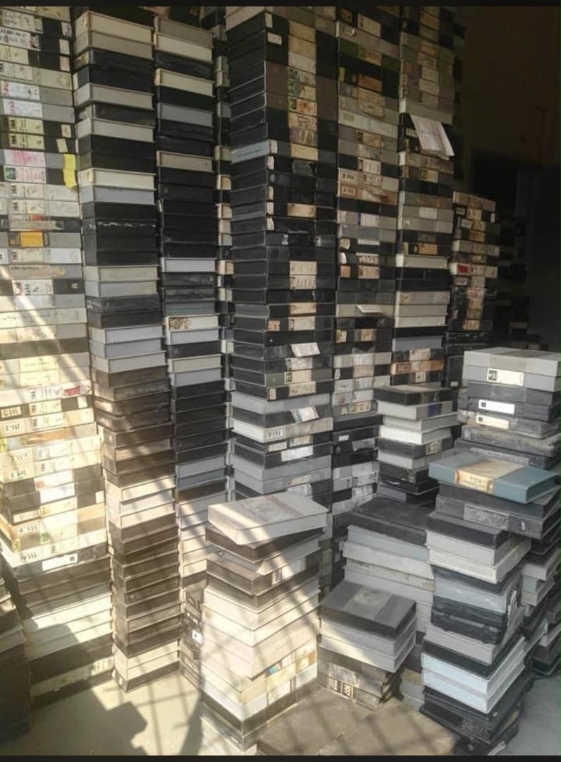 VHS cassettes stacked on the bare floor, awaiting digitisation Sabiya Mapaka